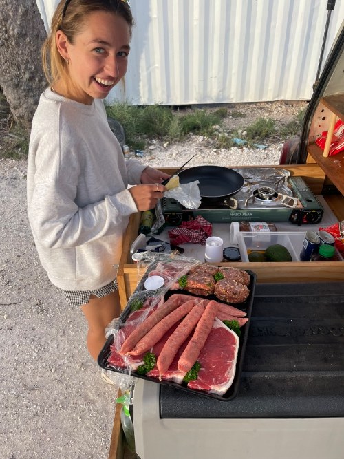 Two people cooking on a camp stove at dusk